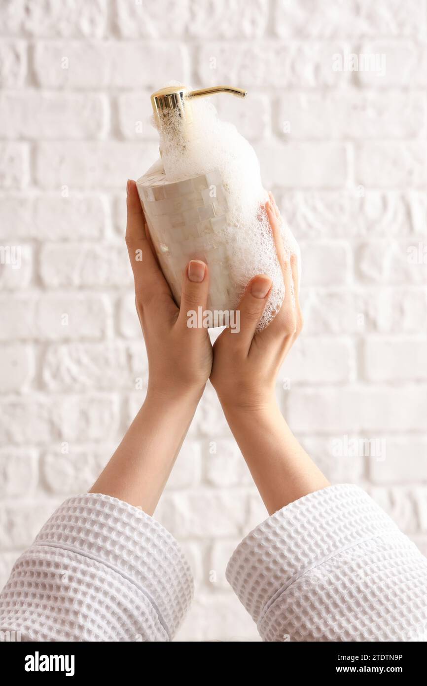 Hands with liquid soap on white brick background Stock Photo