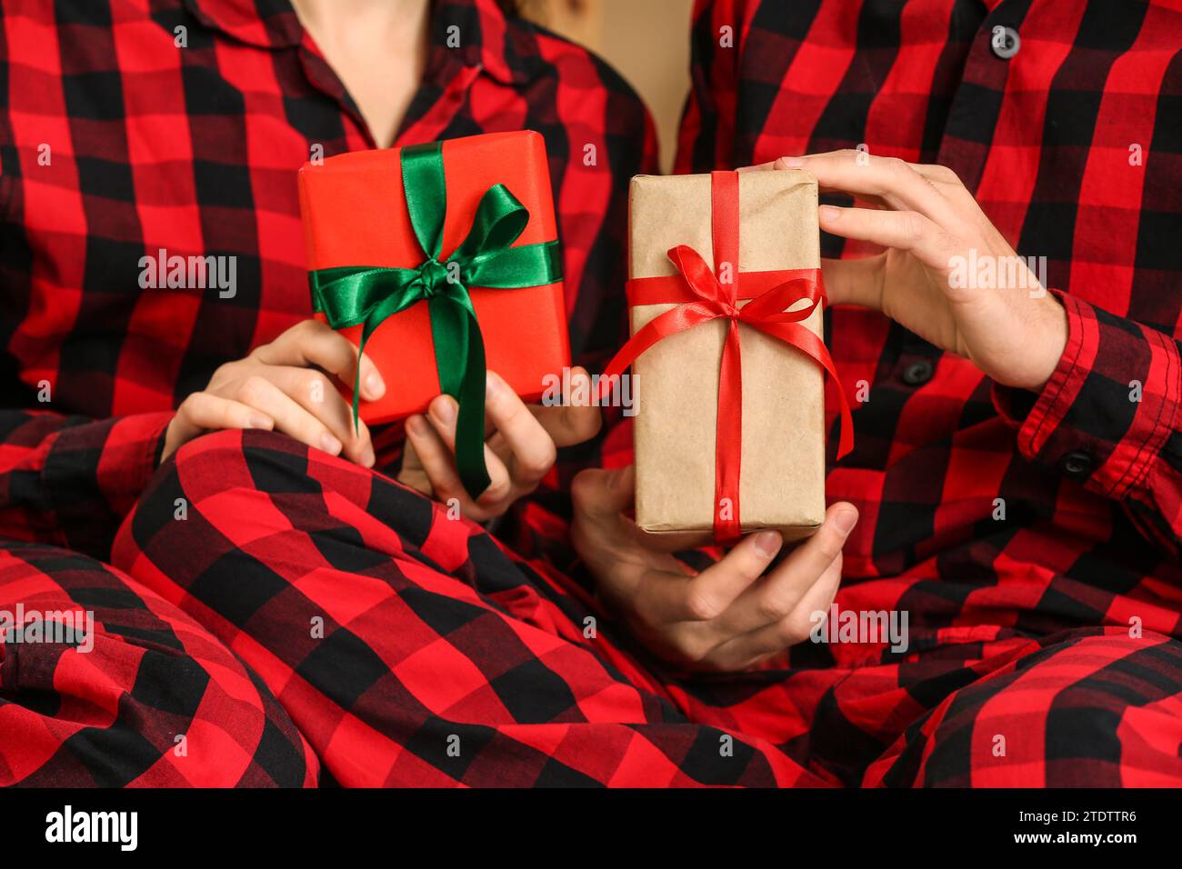 Young couple wearing plaid pajamas with gifts, closeup Stock Photo