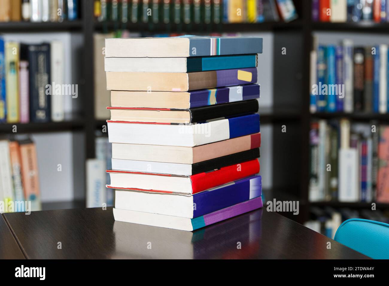 A stack of different books in a large library selected by the reader lies on table Stock Photo