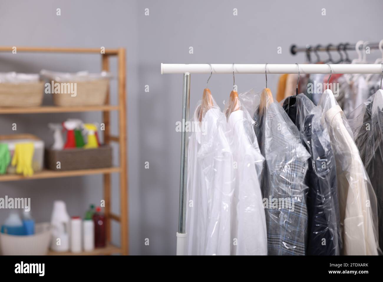 https://c8.alamy.com/comp/2TDXARK/dry-cleaning-service-hangers-with-different-clothes-in-plastic-bags-on-rack-indoors-space-for-text-2TDXARK.jpg