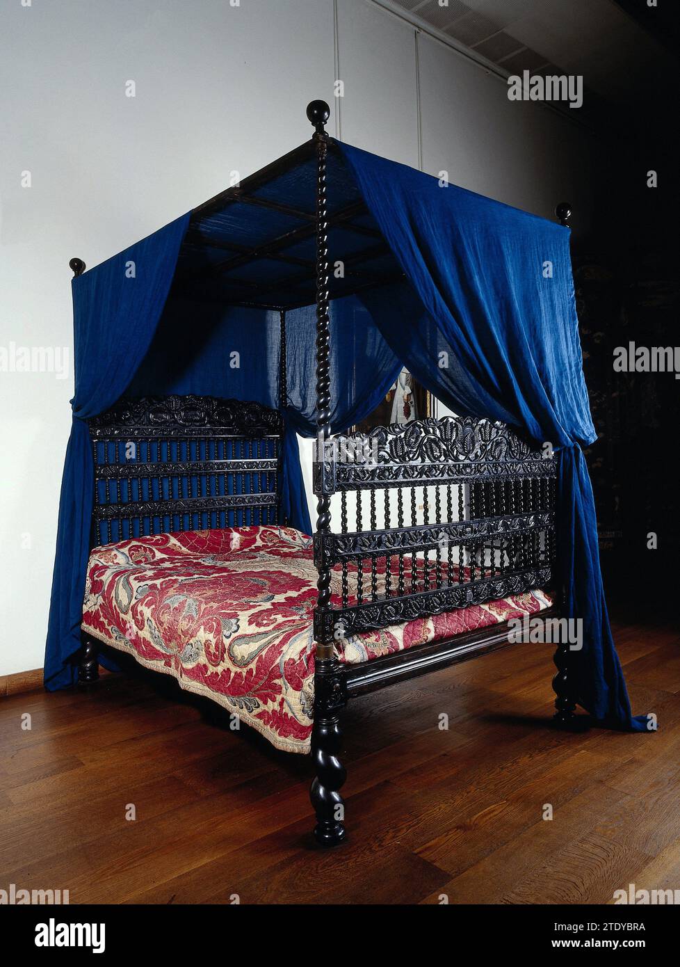 Cot of ebony with cotton heaven. Midden styles and Lotus leaf decorations on sills and houses, Anonymous, c. 1700 Cot of ebony with cotton heaven. The crib rests on four flinged, rejuvenating legs that continue in high styles crowned by bulbs, to which a framework is attached to the cotton heaven. At the headboard, four sills have been installed between these styles, ending in houses and separated by flared colonets; There are three at the foot end. The wide upper sills have a scalloped top edge and the sills a scalloped bottom edge. Surples and houses are decorated with stabbed lotus ranks. B Stock Photo