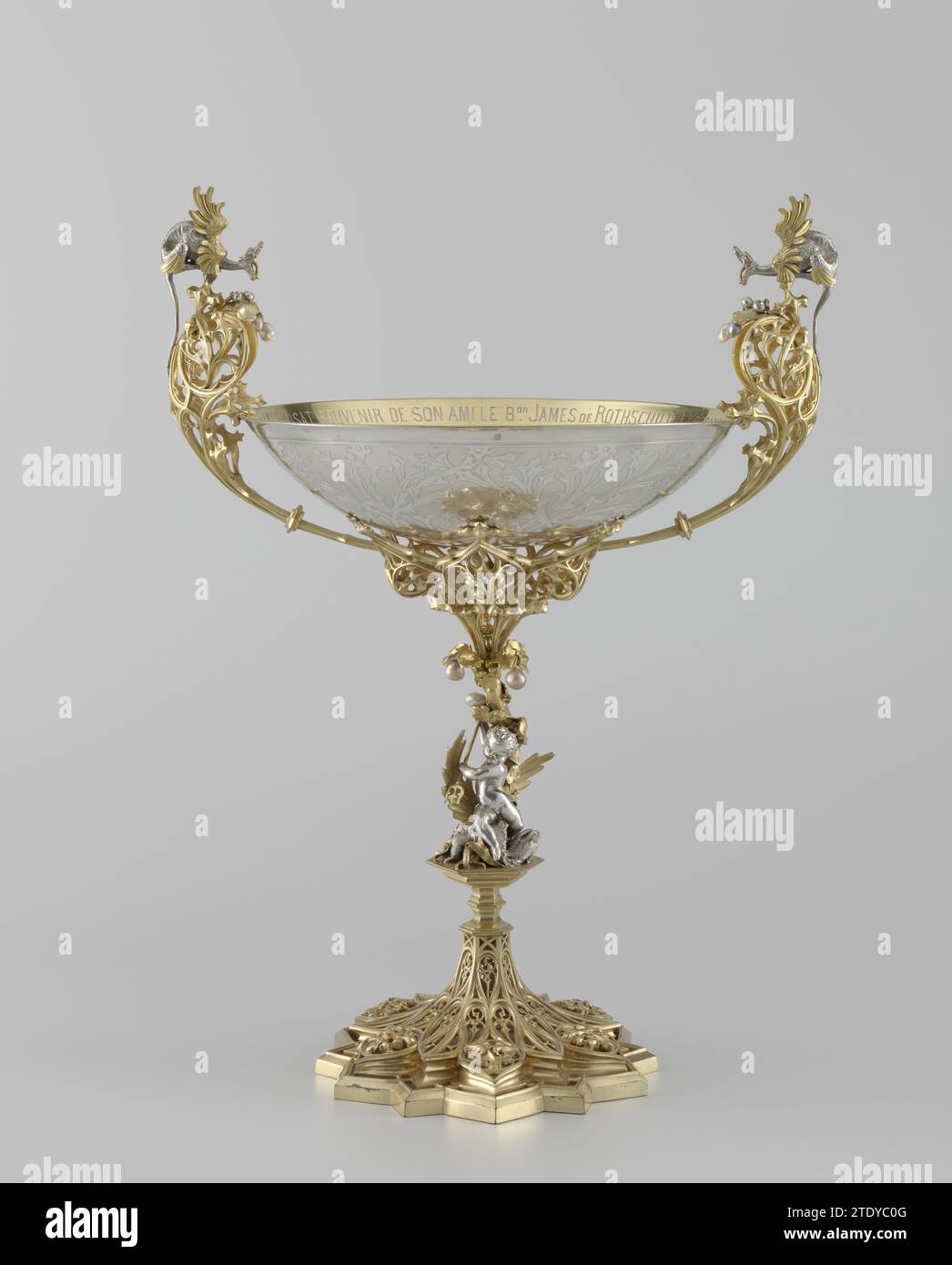 Cup, François Désiré Froment-Meurice, c. 1849 Coupe of partially gilded silver and pearls. Star-shaped rejuvenating foot, decorated with neo-gothic tracing work; tribe in the form of boy who kills dragon with trident; Shapas -shaped upper part with high curled ears crowned by dragons, between which the scale -shaped cuppa. Along the inside of the Cuppa an engraved inscription: A Mr Mel Poisat, Souvenir de Son Ami le Bon James de Rothschild, à l'Occasion du Vingt-Cinquieme Anniversaire de Son Mariage.-le 27 Novembre 1851. Paris silver (metal). pearl. gilding (material) gilding Coupe of partiall Stock Photo