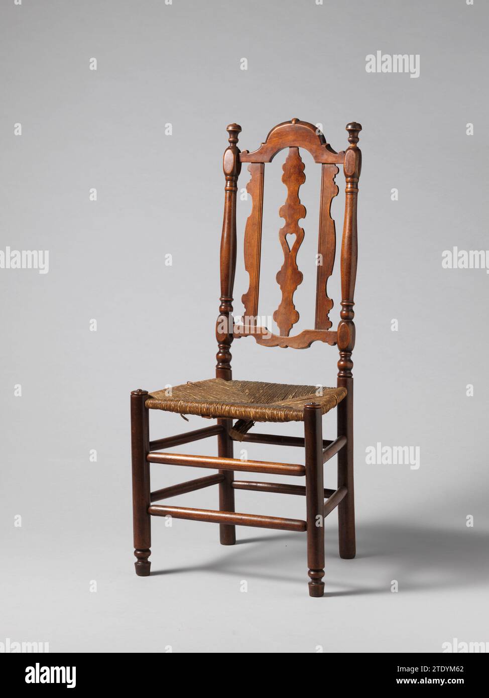 Chair, Anonymous, 1700 - 1750 Chair of cherry wood with mats seat. The legs and eight sports are turned. The corner styles of the back are column -shaped articulated with thickening in the middle. The lower and upper sill are symmetrically sawn out, as well as the middle track that shows an open heart as a middle part and both styles on either side. Vases have been applied as a crowning styles. Northern NetherlandsNetherlands wood (plant material). cherry (wood) Chair of cherry wood with mats seat. The legs and eight sports are turned. The corner styles of the back are column -shaped articulat Stock Photo