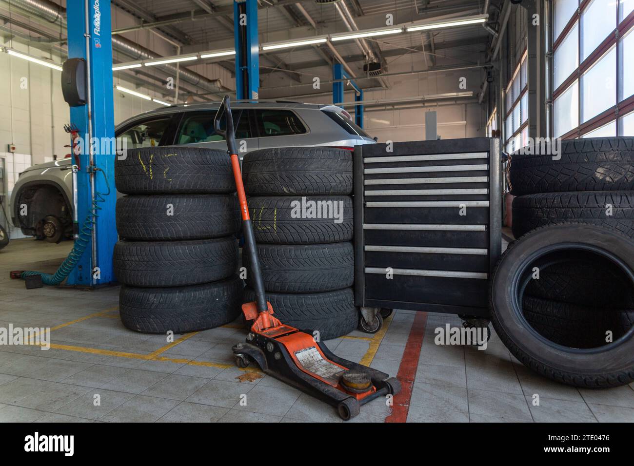 A set of tires for seasonal replacement near the lift in the tire workshop. The concept of seasonal car tire replacement. Stock Photo