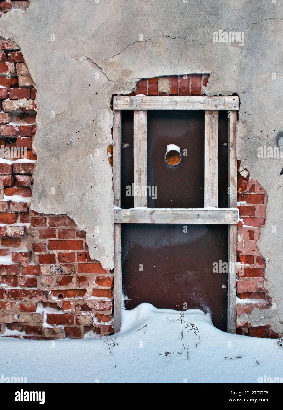damaged plaster on red brick wall in winter Stock Photo