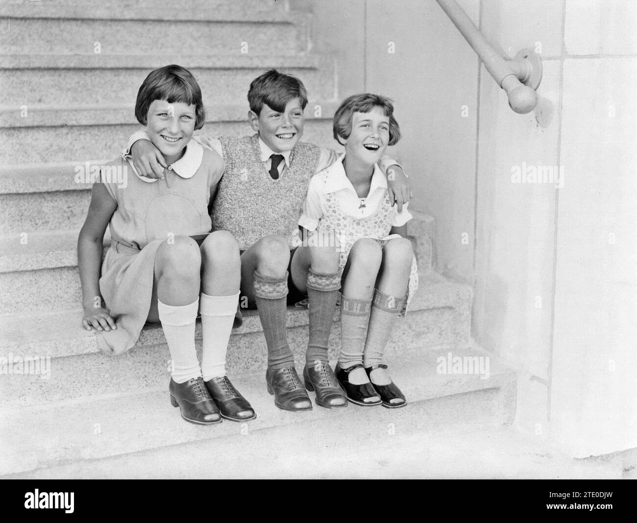 Three friends sitting on steps, smiling and laughing  ca. 1932 Stock Photo