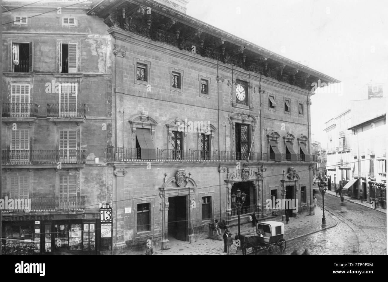 12/31/1912. TOWN HALL HOUSES. It is worth stopping in front of this construction, the result of numerous interventions, and taking a look at the exceptional eaves carved by Gabriel Torres, as well as the clock, located in the central part, which the Mallorcans call En Figuera, in honor of its author, the silversmith Pere Joan Figuera. On the ground floor the Gothic portal of the Sant Andreu chapel is preserved and the gegants de Cort (the giants of Cort) stand proudly, dressed in the typical Mallorcan costume. Two of these enormous peasants flank the marble staircase that leads to the upper fl Stock Photo