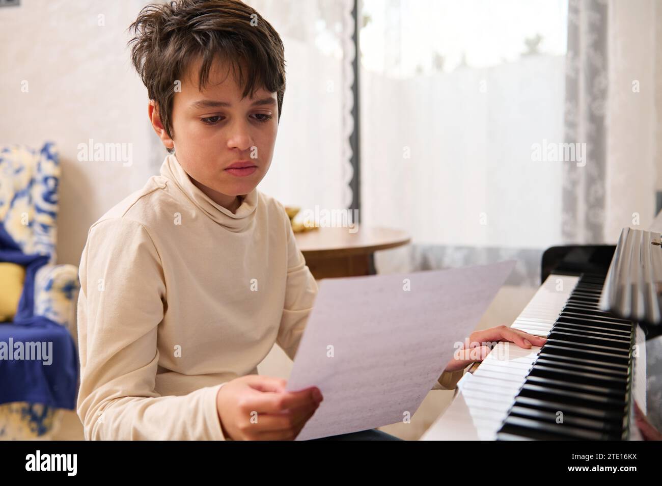 Adorable multi ethnic teenage boy learning musical notes, sitting at ...