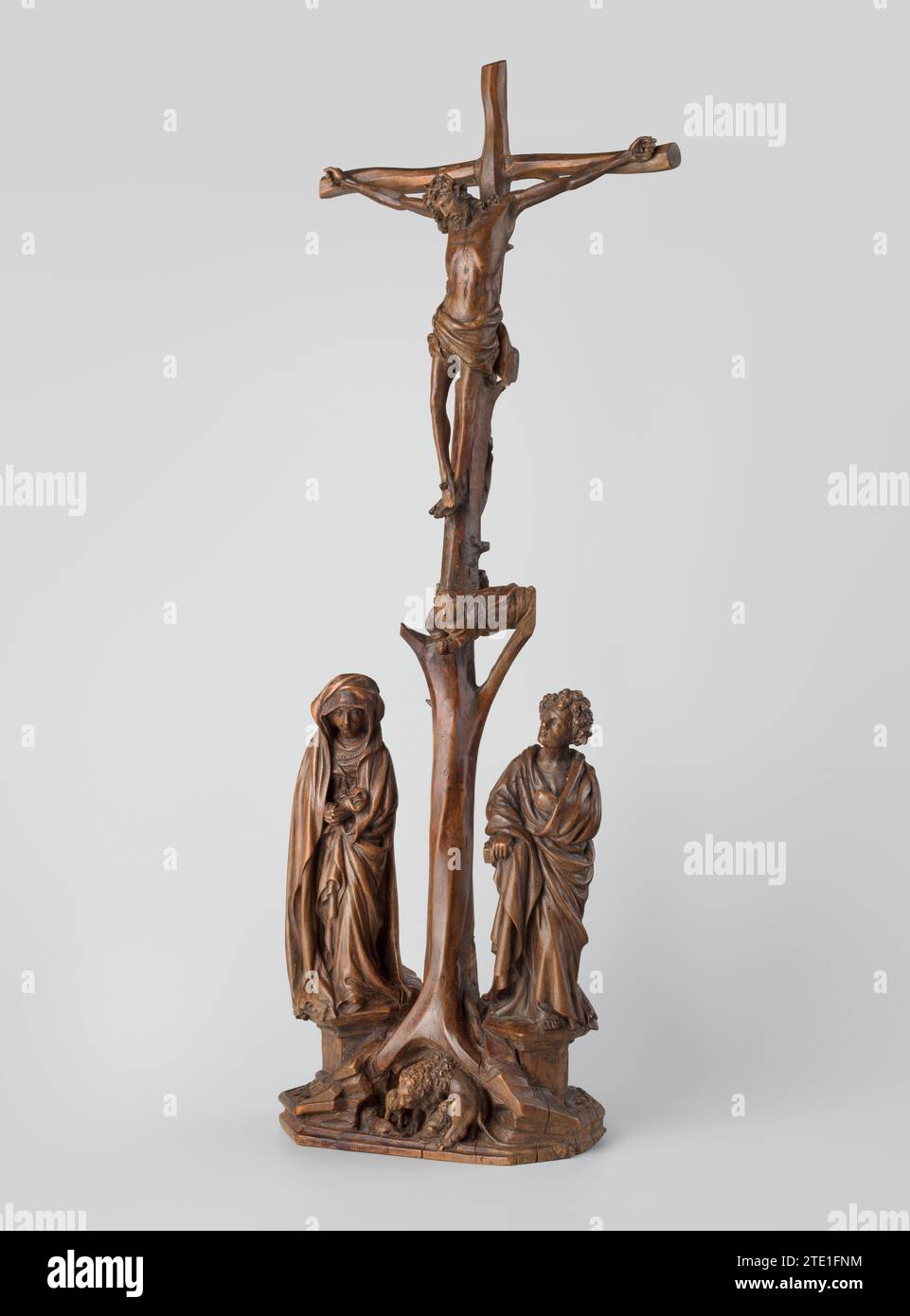 Calvary, Claus Sluter, c. 1390 - c. 1410 The crucifixion of Christ, flanked by his mother Mary and John the Evangelist, both standing on a small pedestal. The slender and somewhat backwards crossed cross is made in the form of a real truncated tree trunk and carrots in a naturalistic rock base that is elongated heptagonal and finished with a profile edge and a piped acanthus leaves. Halfway through, an angel floats between a dead, sawn -down side branch of the trunk. In the middle of the tree roots is a cave in which a lioness takes care of her cubs.  boxwood (hardwood) cutting The crucifixion Stock Photo