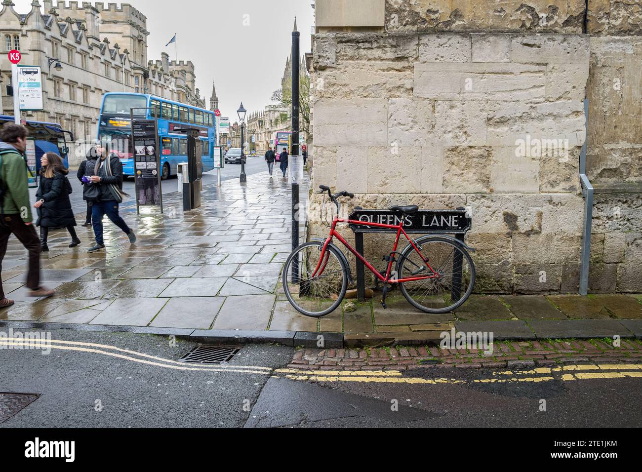 rainy day in Oxford, England with bicycle parked against the sign for Queen's Lane Stock Photo