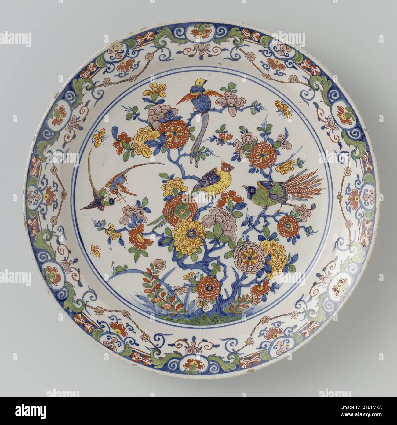 Saucer, multi -colored painted with chinoiserie, anonymous, c. 1715 - c. 1740 Dish of Faïence, multicolored painted with chinoiserie: on the flat a flower with birds. Rand of lambrequins. Delft . Dish of Faïence, multicolored painted with chinoiserie: on the flat a flower with birds. Rand of lambrequins. Delft . Stock Photo