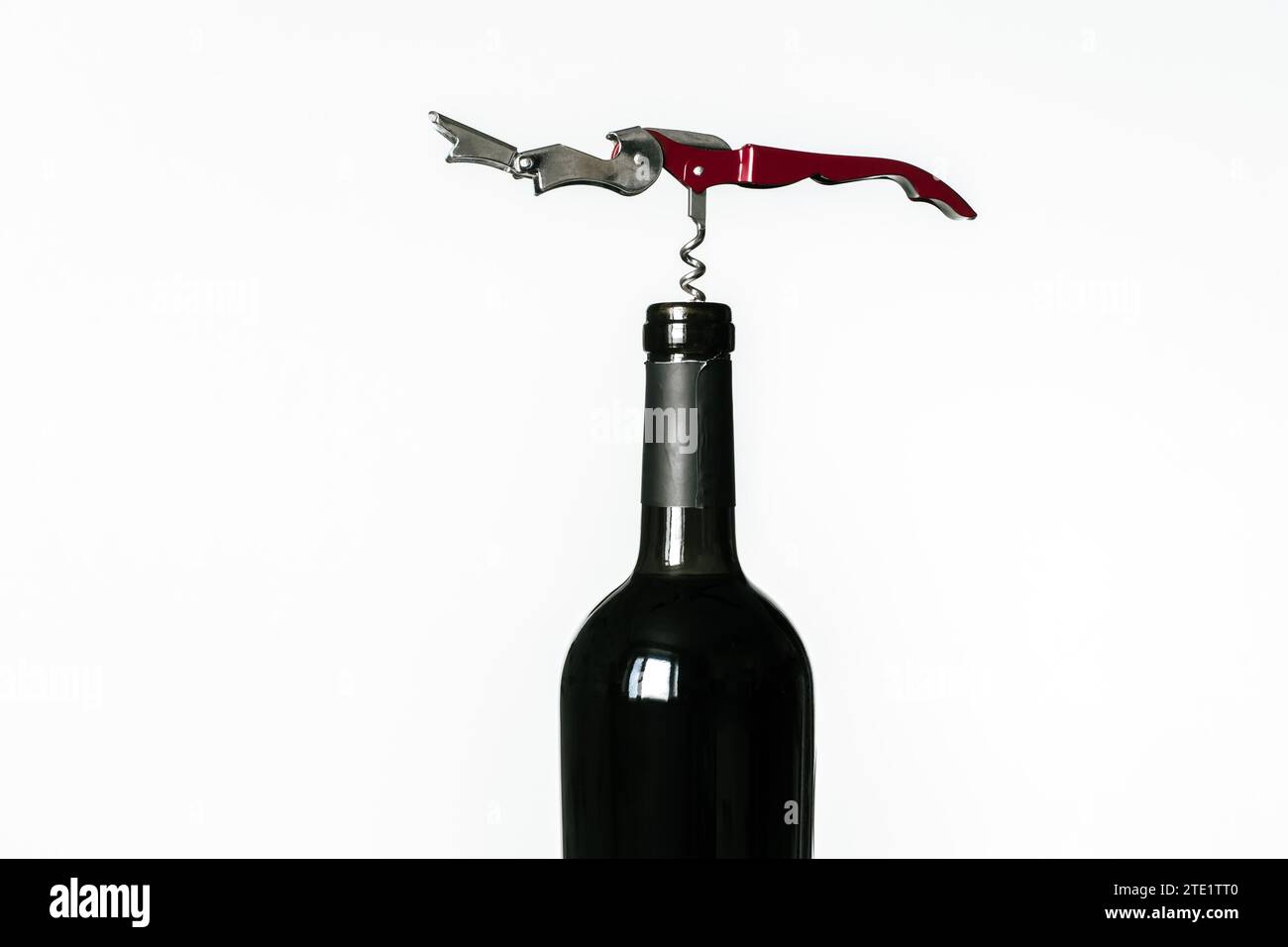 Corkscrew screwed into the cork of a bottle of red wine isolated on a white background Stock Photo