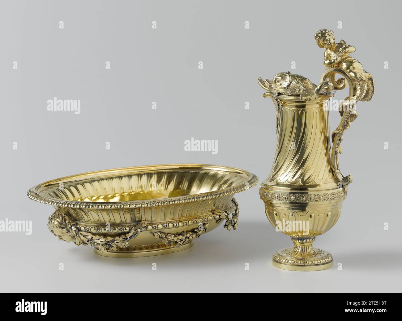 Ewer and basin, Thomas Chancellier, 1765 Water can of gilded silver. The can rest on a rising base, has a convex bottom with a blasted godrons and, above a profile with rosettes, a high concave neck on which the godrons runs. The lid is formed as the head of a dolphin. A crowning sea-putting winds its double tail around the high rising ear. Paris silver (metal). gilding (material) gilding Water can of gilded silver. The can rest on a rising base, has a convex bottom with a blasted godrons and, above a profile with rosettes, a high concave neck on which the godrons runs. The lid is formed as th Stock Photo