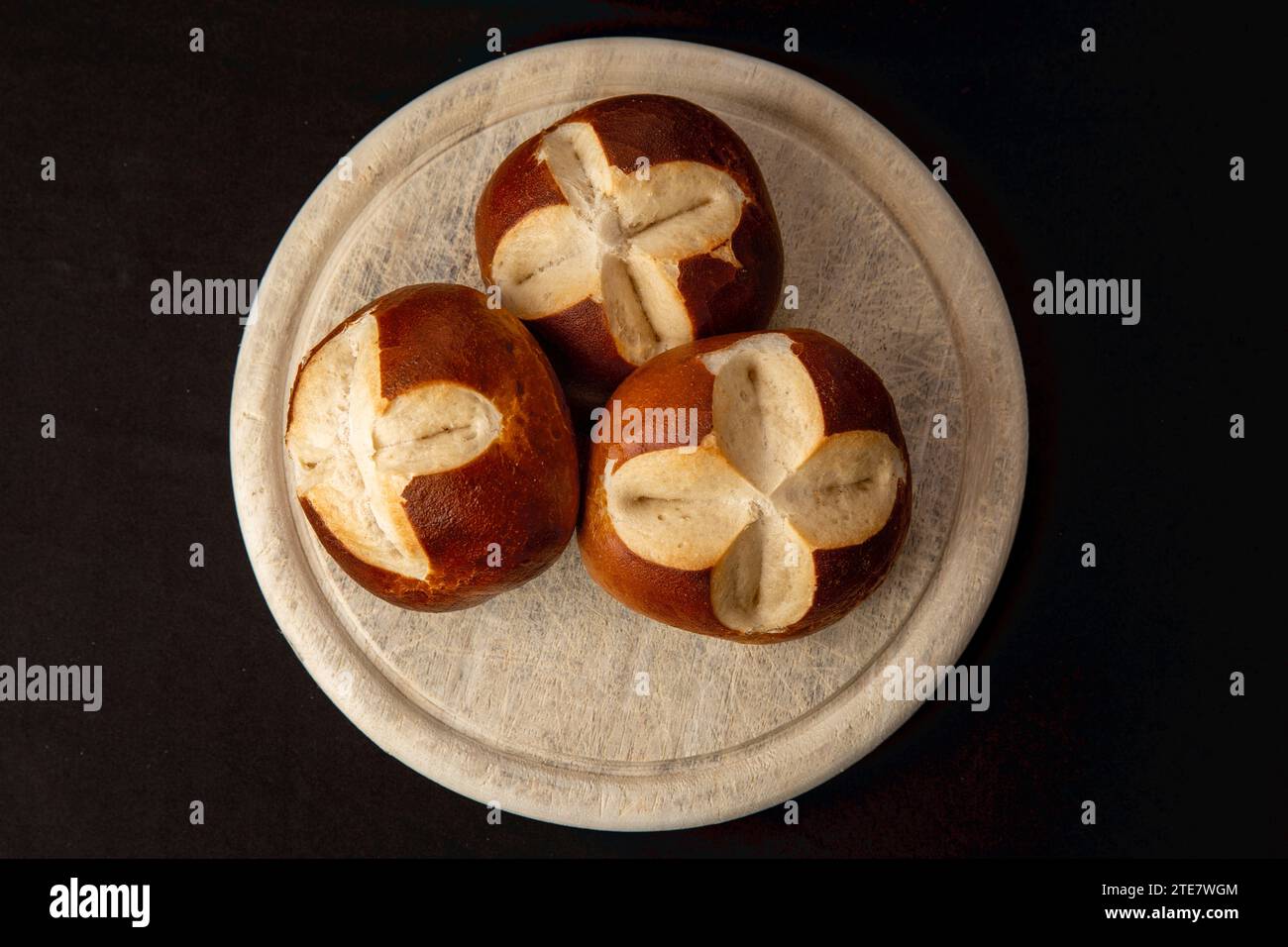 German Pretzel Rolls on Wood Plate on Black Background Stock Photo