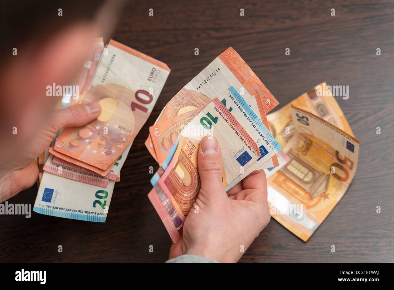 Hamburg, Germany - December 2, 2023: Man counts a large amount of cash euro bills *** Mann zählt eine große Menge Bargeld Euro Scheine Stock Photo