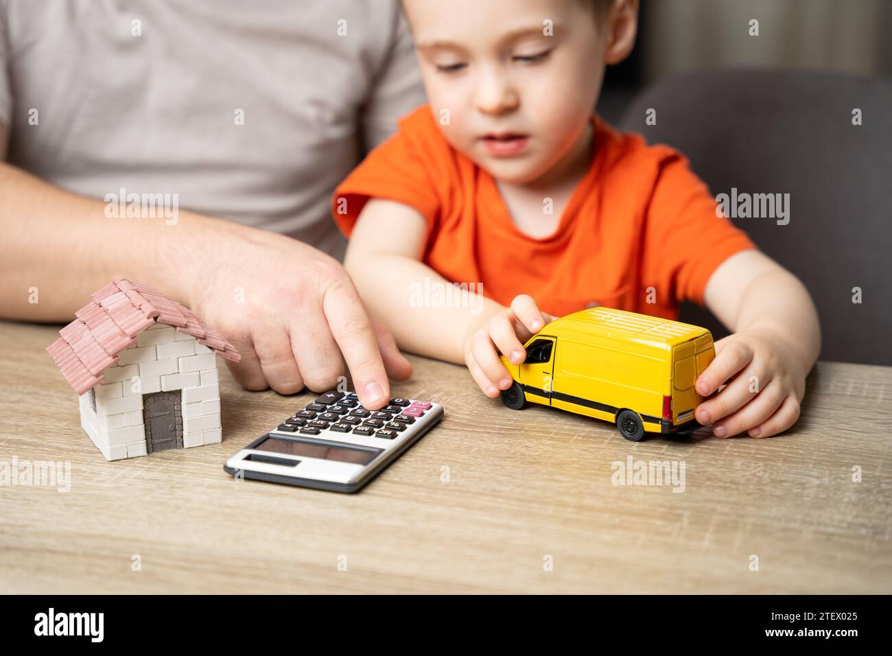 Home moving. Sending and receiving parcels and online orders. A child and his father calculate the cost of transporting boxes on a calculator. Stock Photo