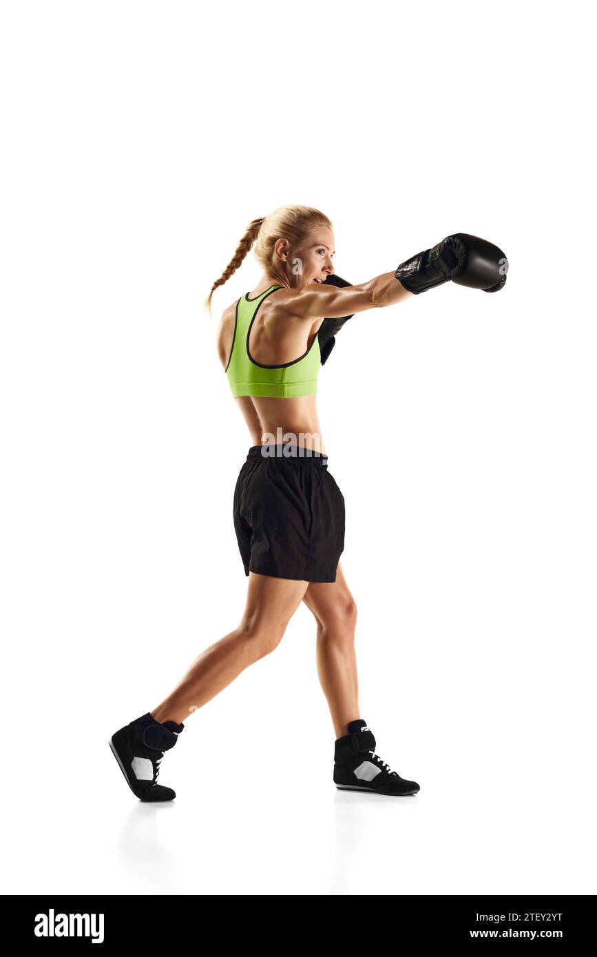 Jab punch. Young sportive woman with muscularly fit body practicing boxing isolated over white background. Sport, healthy and active lifestyle Stock Photo
