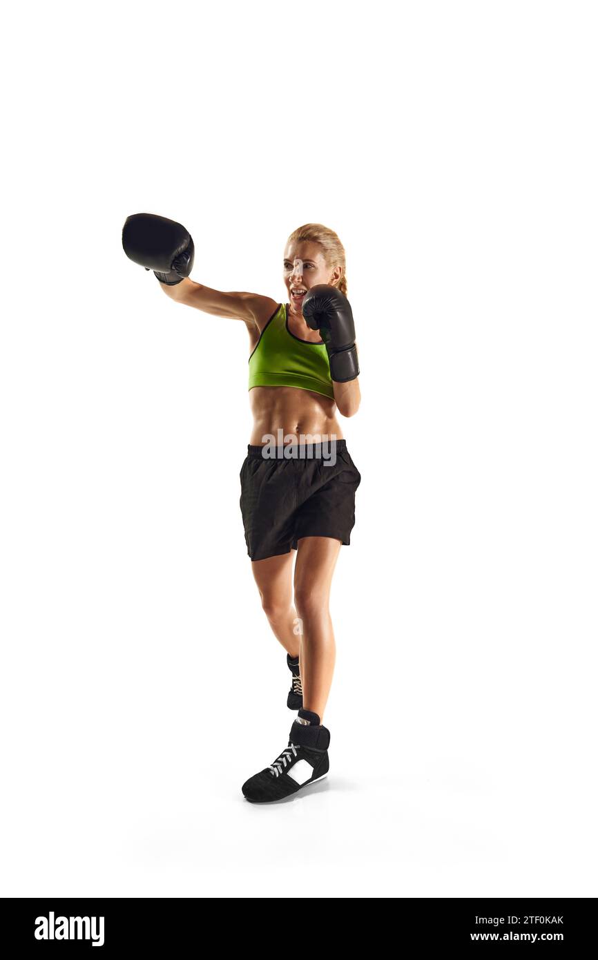 Muscular, concentrated young woman, boxing athlete training, punching isolated over white background. Sport, healthy and active lifestyle Stock Photo
