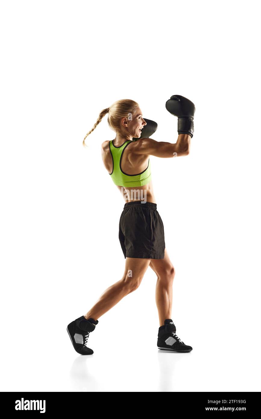 Upper cut punch. Young woman with muscular fit body training, boxing athlete practicing isolated over white background. Sport, healthy and active Stock Photo