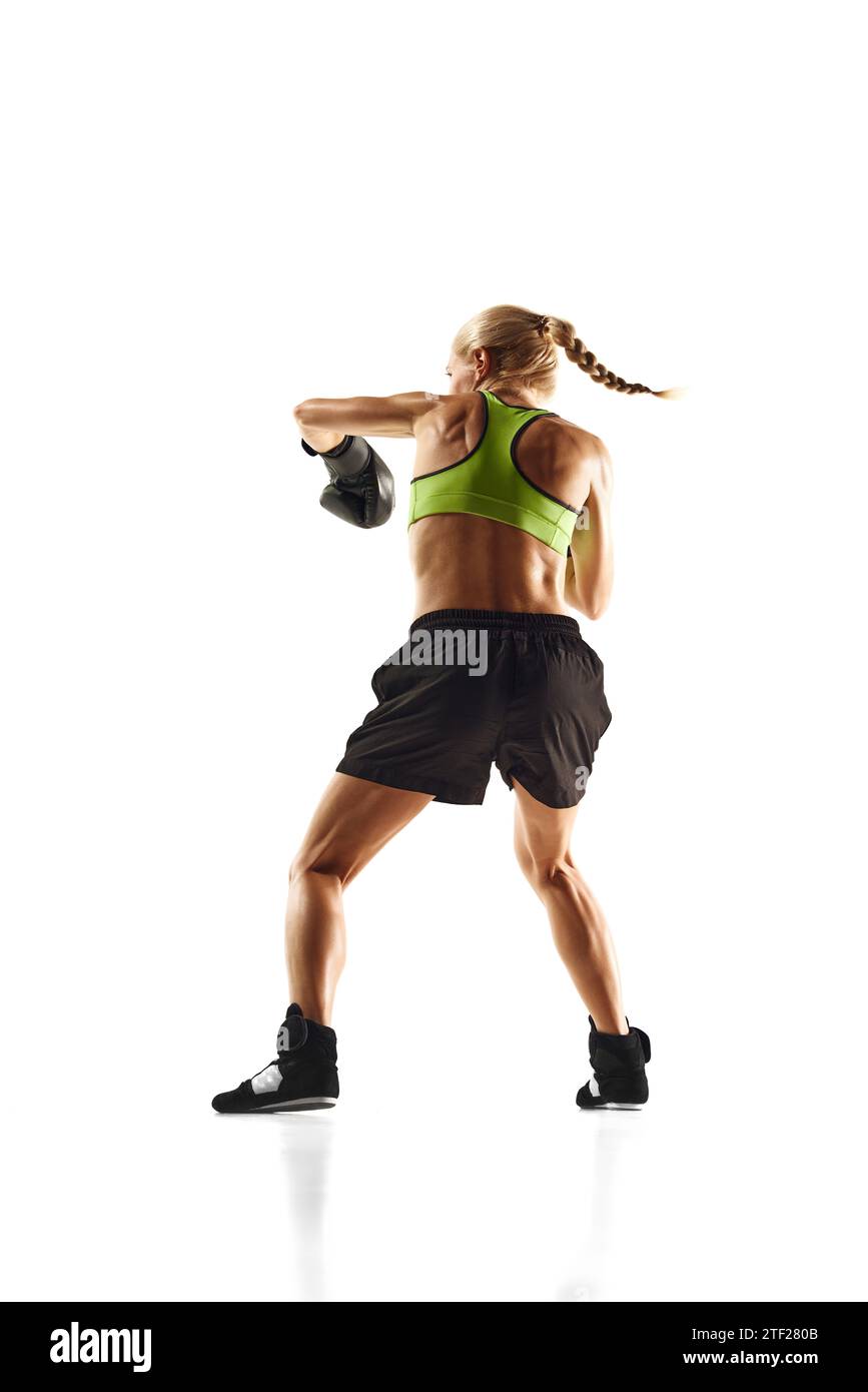 Muscular young woman, boxing athlete practicing, punching, training isolated over white background. Sport, healthy and active lifestyle Stock Photo