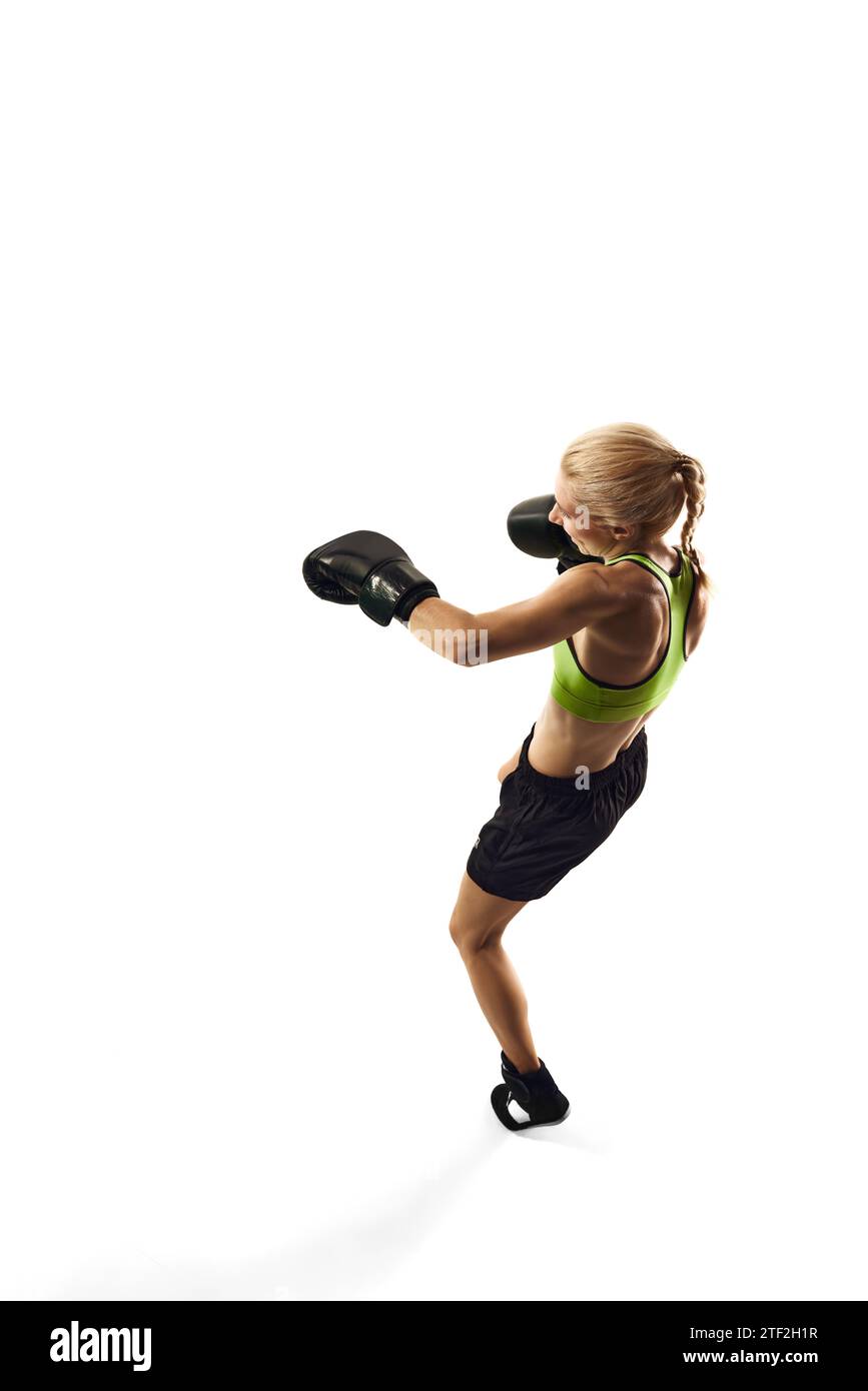 Left hook punch. Sportive young woman, boxing athlete with slim muscular body training isolated over white background. Sport, healthy and active Stock Photo