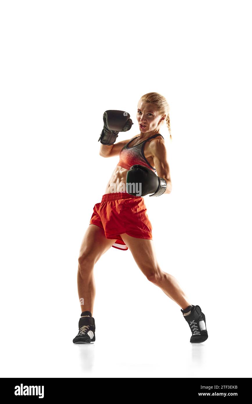 Bottom view of muscular young woman, boxing athlete in motion, training, punching isolated over white background. Sport, healthy and active lifestyle Stock Photo