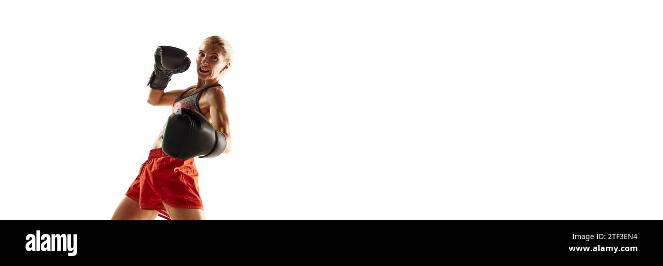 Young woman with fit, muscular body, boxing athlete in uniform, training isolated over white background. Sport, healthy and active lifestyle Stock Photo
