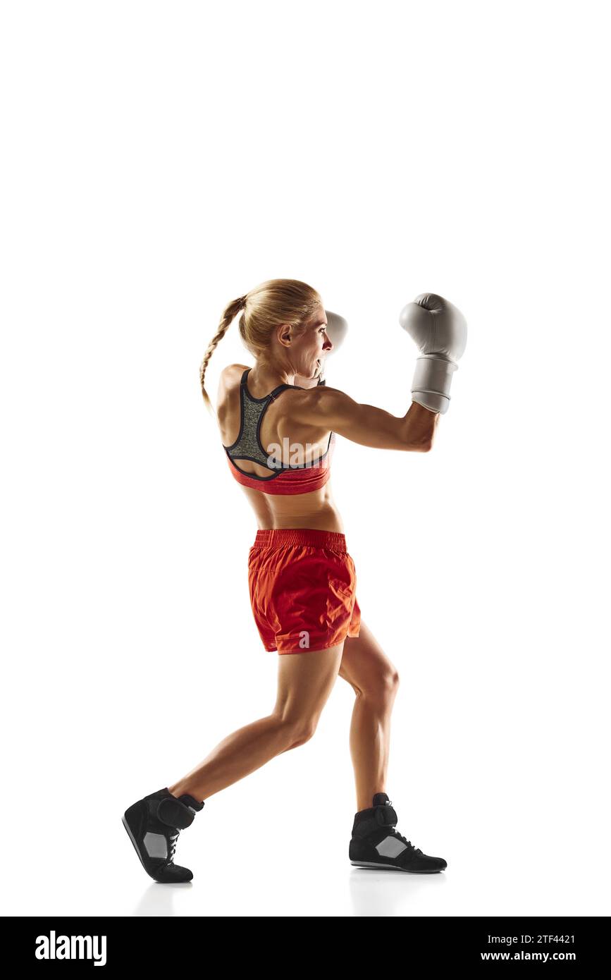 Muscular, competitive boxing athlete, young woman in motion training, practicing, punching isolated over white background. Sport, healthy and active Stock Photo