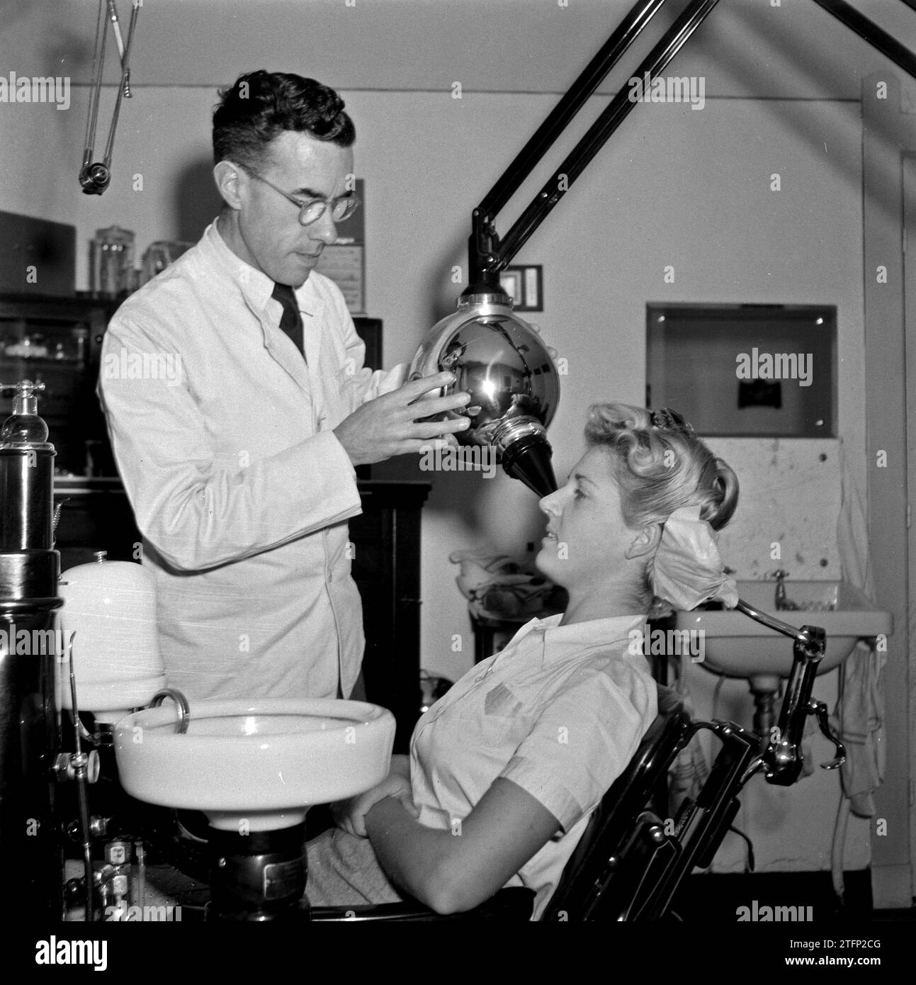 1940s Dental practice with dentist working on a female patient and a