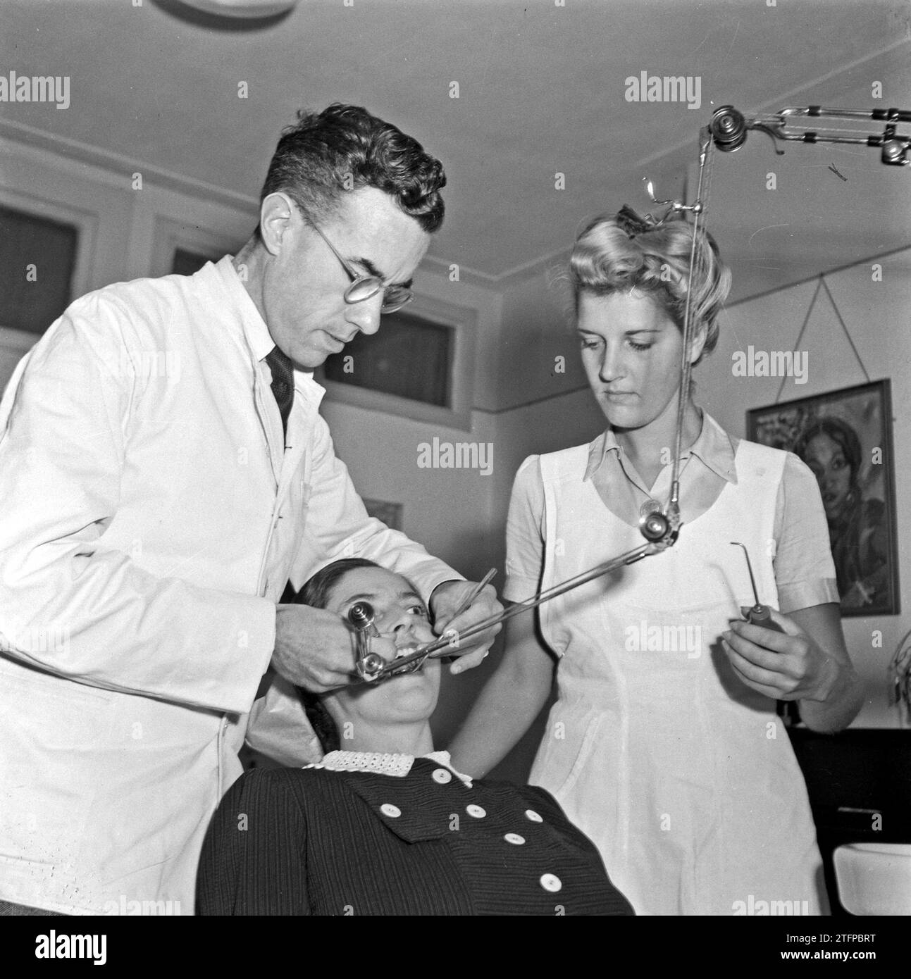 1940s-dental-practice-with-dentist-working-on-a-female-patient-and-a