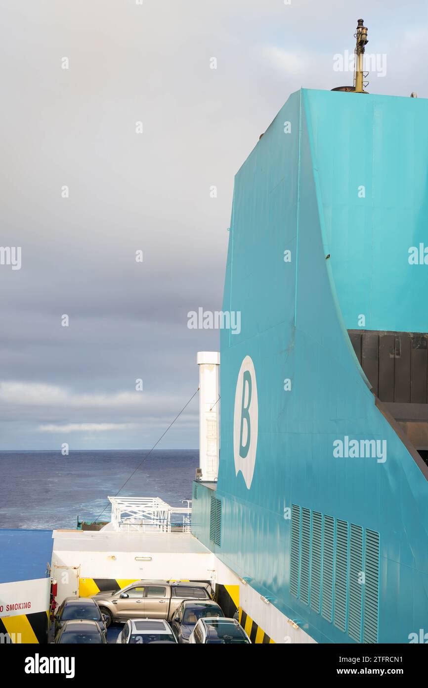 Large turquoise ferry with a prominent white logo from Balearia. Towering structure of the ship against a backdrop of a cloudy sky transitioning to du Stock Photo