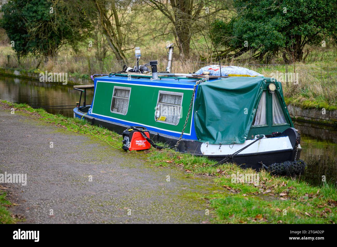 Small narrowboat charging its batteries with a portable petrol generator. Stock Photo