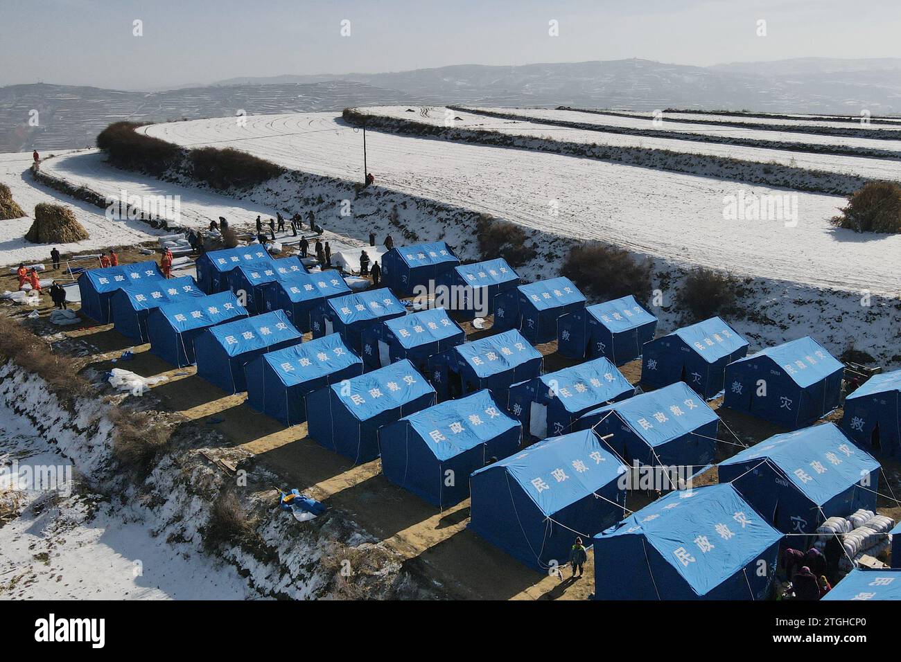 (231220) -- LINXIA, Dec. 20, 2023 (Xinhua) -- This aerial photo taken on Dec. 20, 2023 shows rescuers setting up tents at a temporary relocation site in Shenjiaping Village of Jishishan County, northwest China's Gansu Province. All-out rescue and relief work are underway amid bitter cold as a 6.2-magnitude earthquake has killed 113 people and injured 782 others in northwest China's Gansu Province, according to a press conference on Wednesday. A total of 87,076 people from 20,457 households have been temporarily relocated to safe places. Emergency relief materials such as tents, quilts, fo Stock Photo