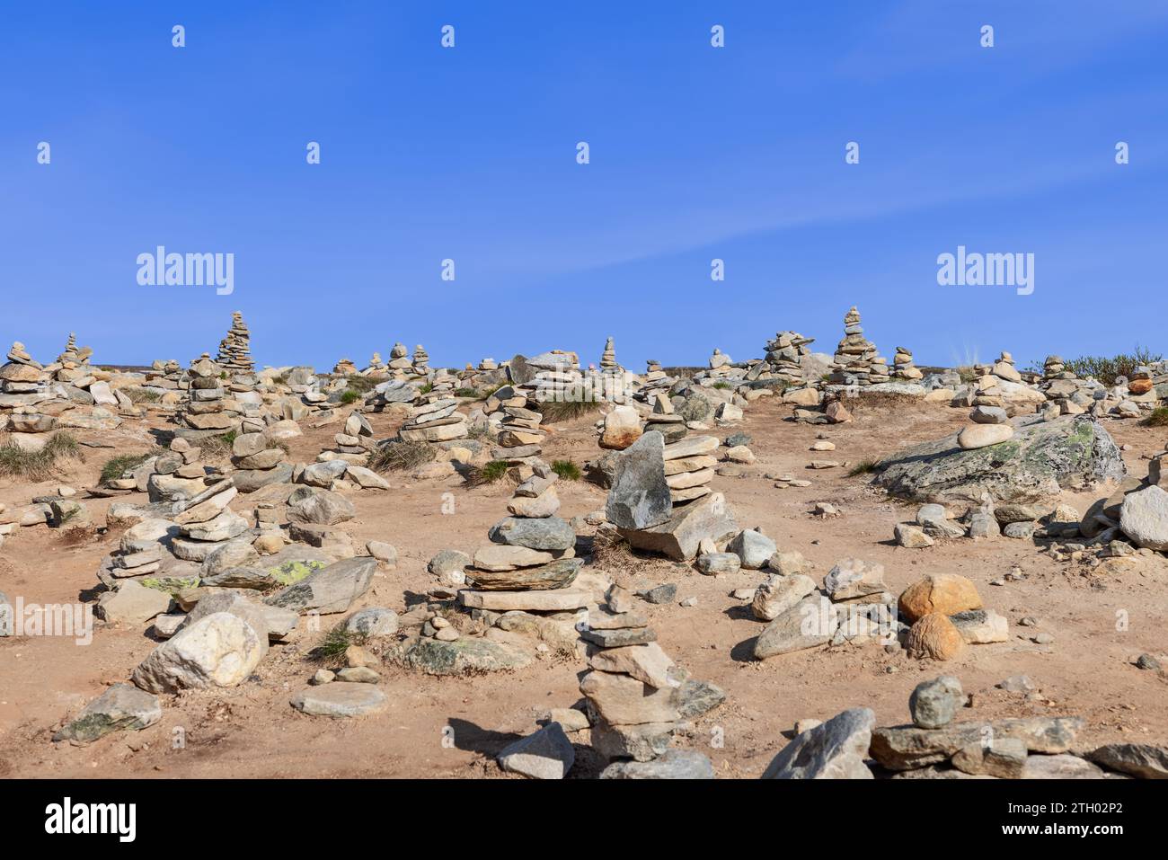 Stone pyramids, meticulously assembled by visitors near the Arctic Circle Center in Rana, Nordland, Norway, stand under a clear blue summer sky Stock Photo