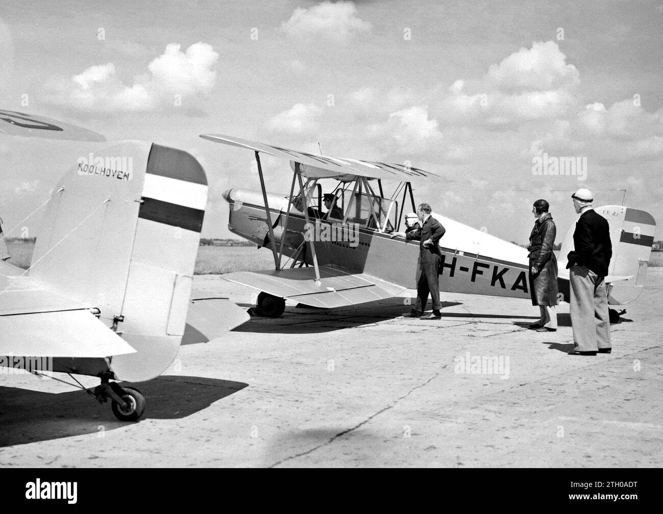 A Koolhoven FK-46 training plane nicknamed 'Koe or Koebeest' because of its docile flying behavior of the National Aviation School Holland at Amsterdam Schiphol with instructor and aspiring pilot, standing a mechanic and two student pilots ca. 1933 Stock Photo