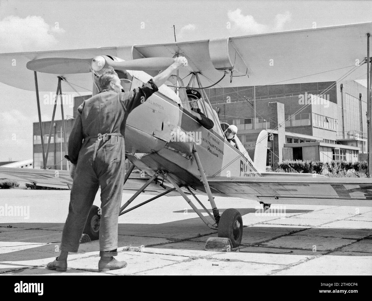 The mechanic turns on the propeller of the Koolhoven FK-46 training aircraft because of its docile flying behavior nicknamed 'Koe or Koebeest' of the National Aviation School Holland at Amsterdam Schiphol, while the instructor and aspiring pilot lean out of the cockpit ca. 1933 Stock Photo