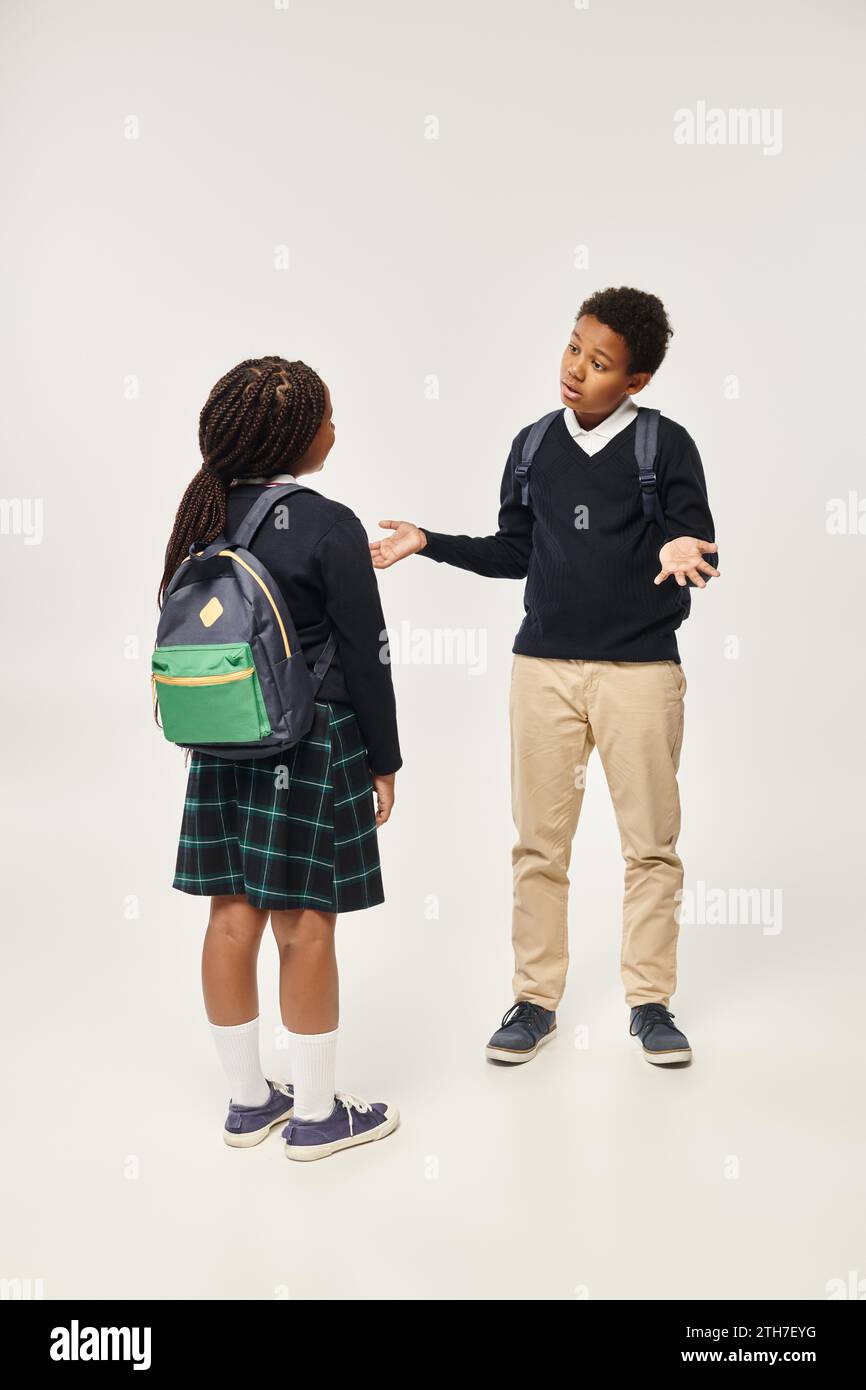 african american schoolkids with backpacks standing together and chatting on grey background Stock Photo