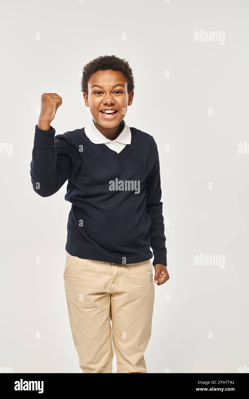 excited african american schoolboy in neat uniform rejoicing while