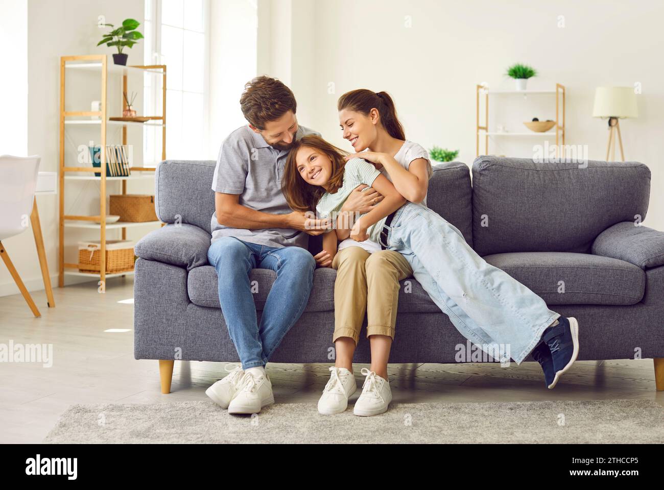 Happy, loving family spending time together and hugging on the couch in the living room Stock Photo