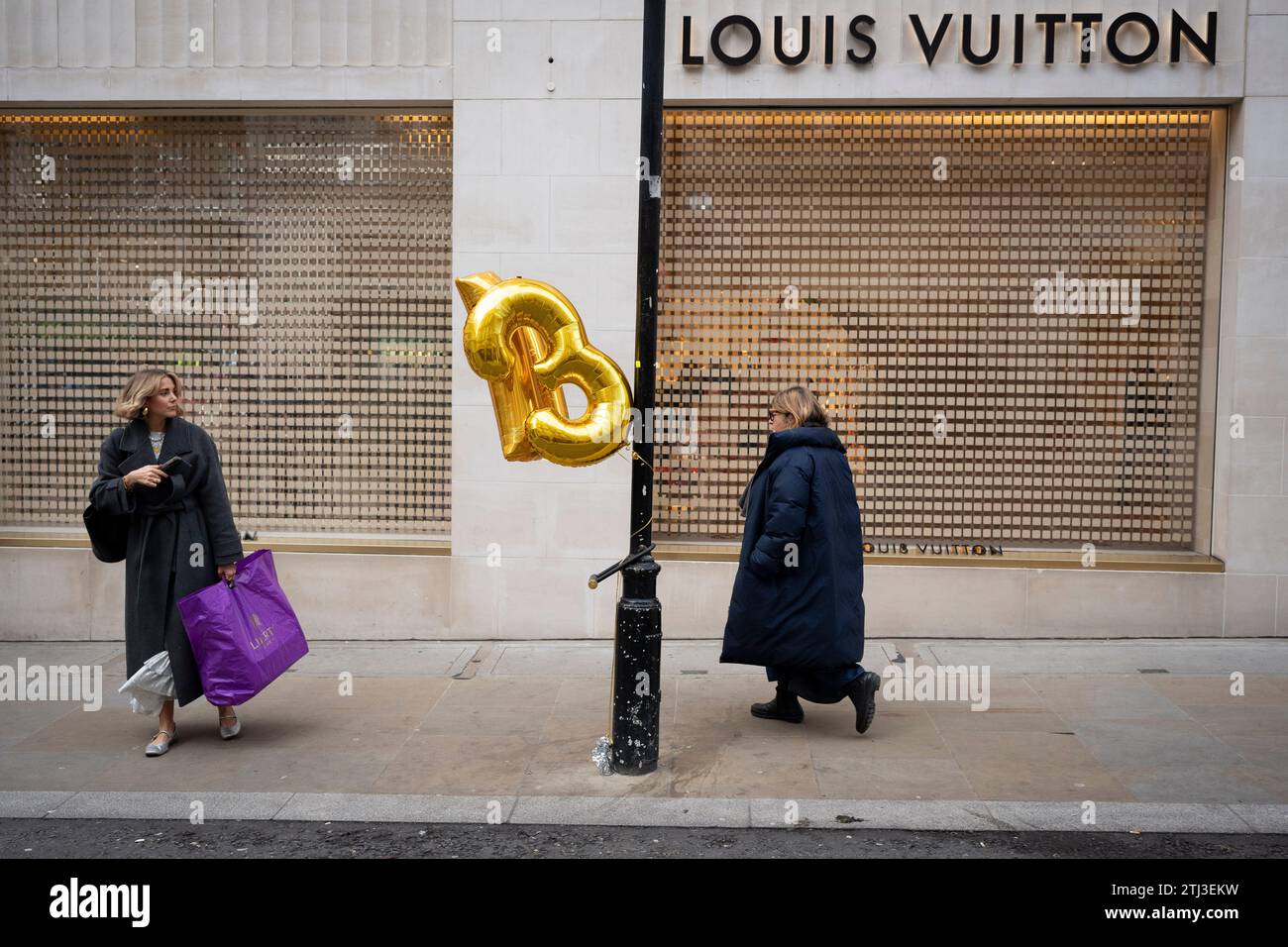 Christmas shoppers and helium balloons tied to a lamp post outside LLouis Vuitton on New Bind Street, on 20th December 2023, in London, England. Stock Photo
