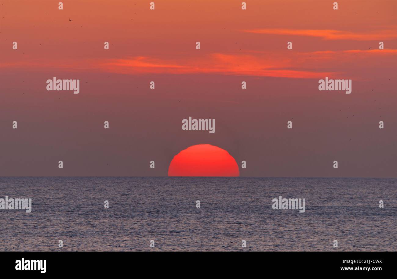 The Setting sun. A red/orange disc in the sky. Stock Photo