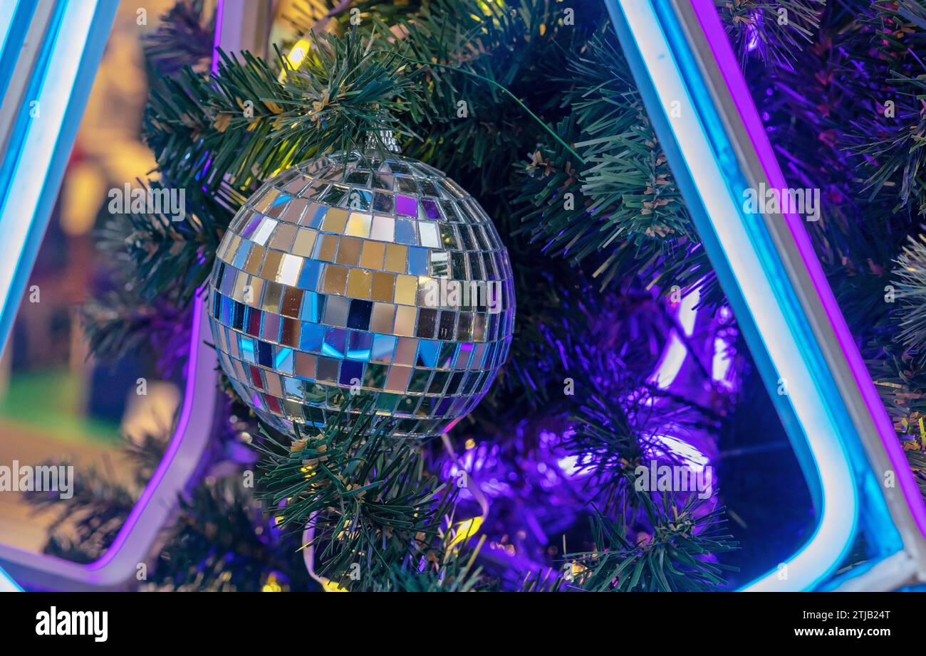 Disco Mirror Ball in neon light on a Christmas tree. Stock Photo