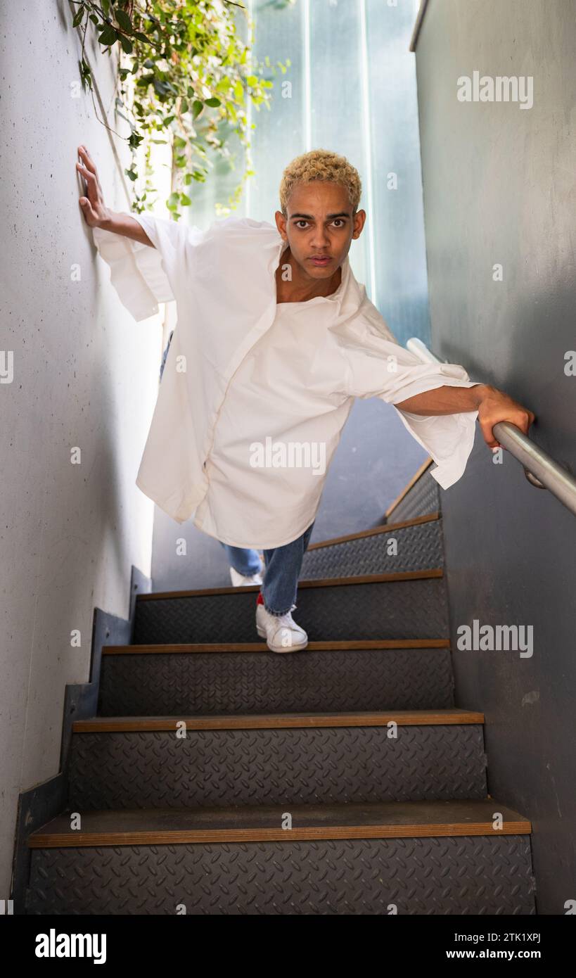 Modern black young man with beautiful blond hair posing on the stairs of the building Stock Photo
