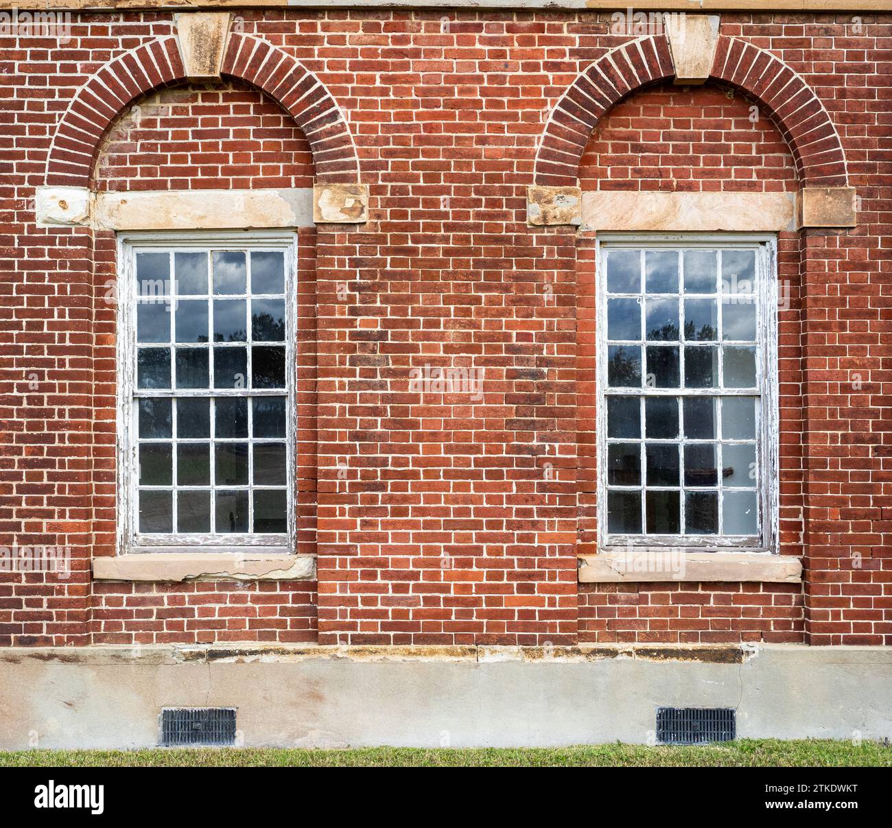 An intricate red brick facade at Fort Washington in Virginia boasts a symmetrical arrangement of captivating windows, evoking an enchanting architectu Stock Photo