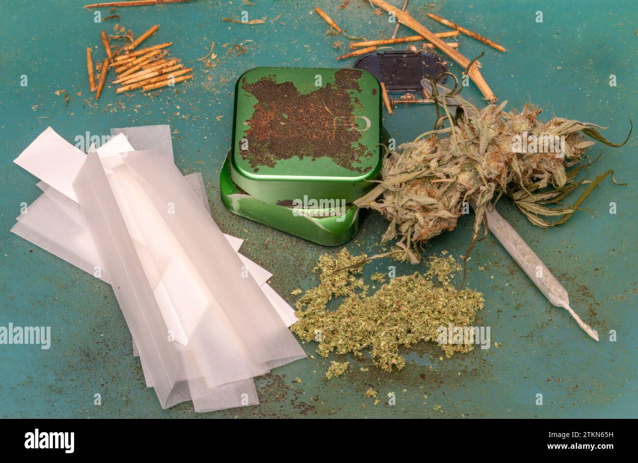 Rolling white papers with green dry weed and joint with metallic