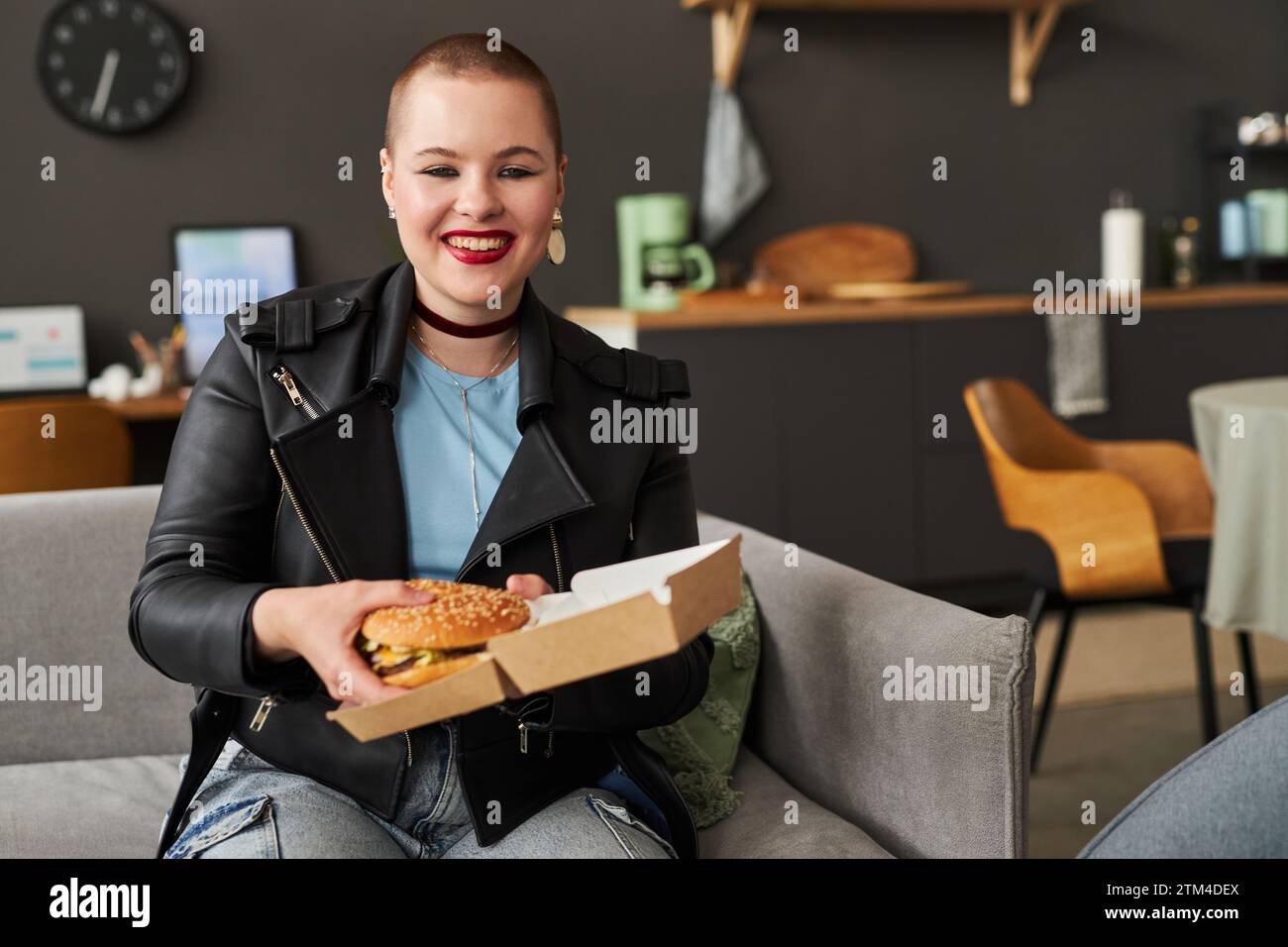 Cheerful Young Girl Holding Cardboard Box with Burger Stock Photo