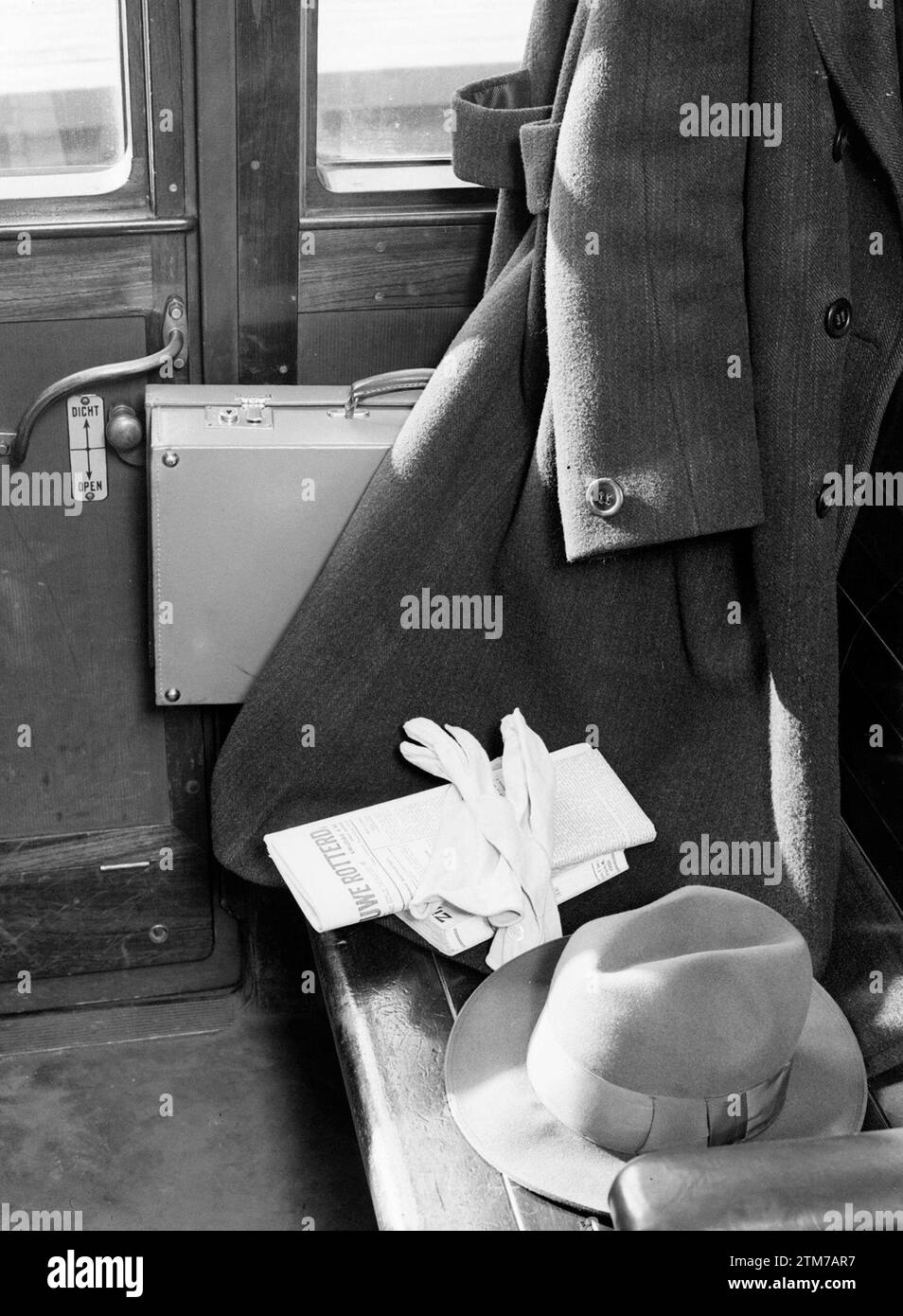 Interior of a train compartment: hung coat, hat, gloves, newspaper, suitcase and benches ca. 1932 Stock Photo