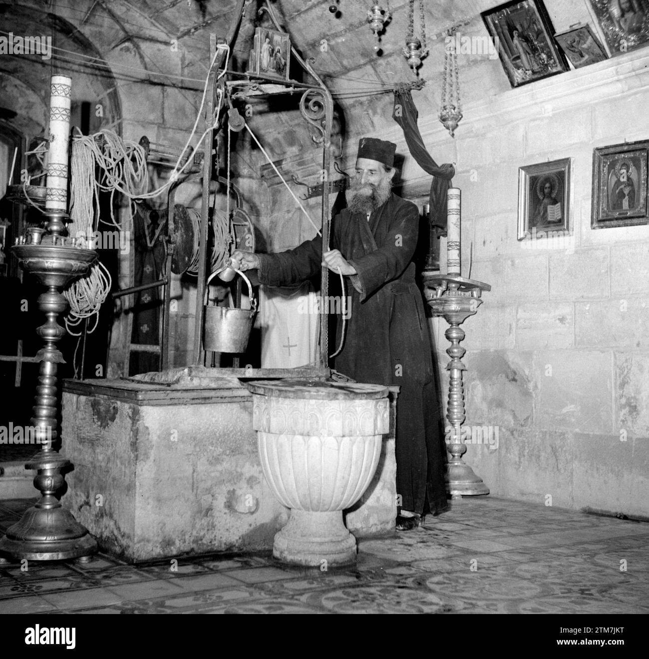 Near Nablus. Priest lifts bucket of water from Jacob's well ca. 1950