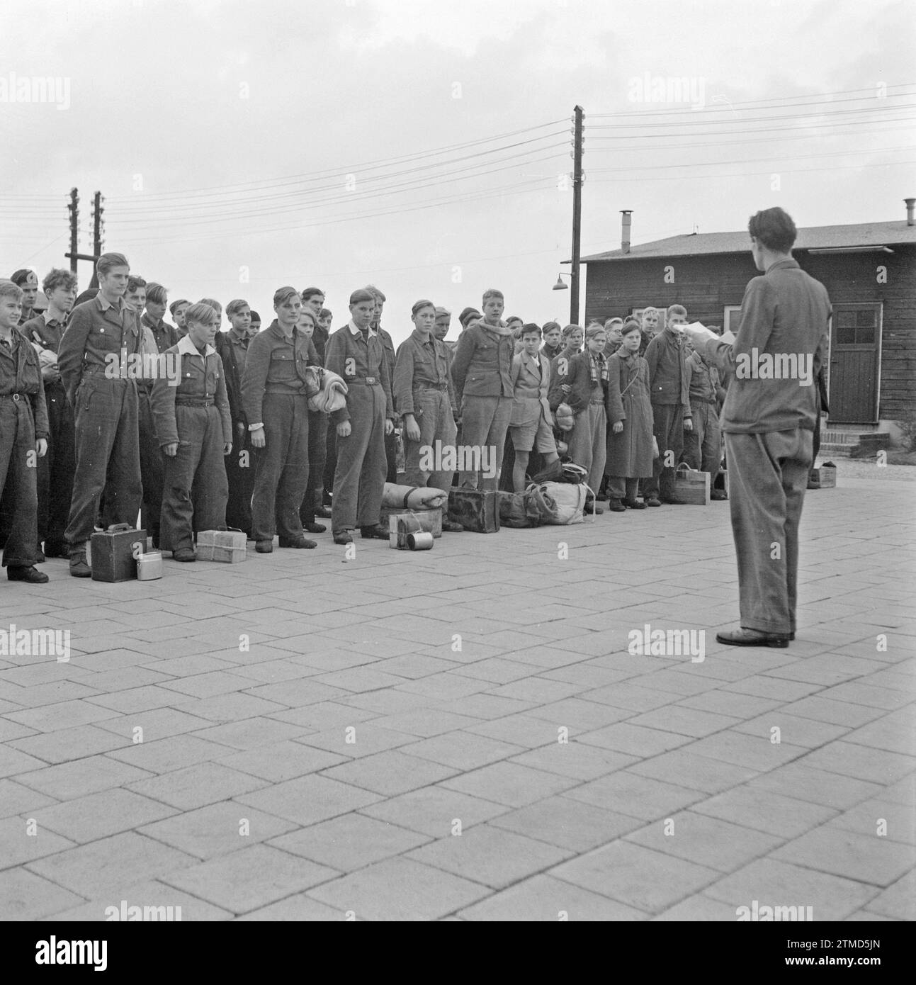 Boys are lined up with luggage, some in a kind of uniform. They are addressed by a man ca. October 1945 Stock Photo