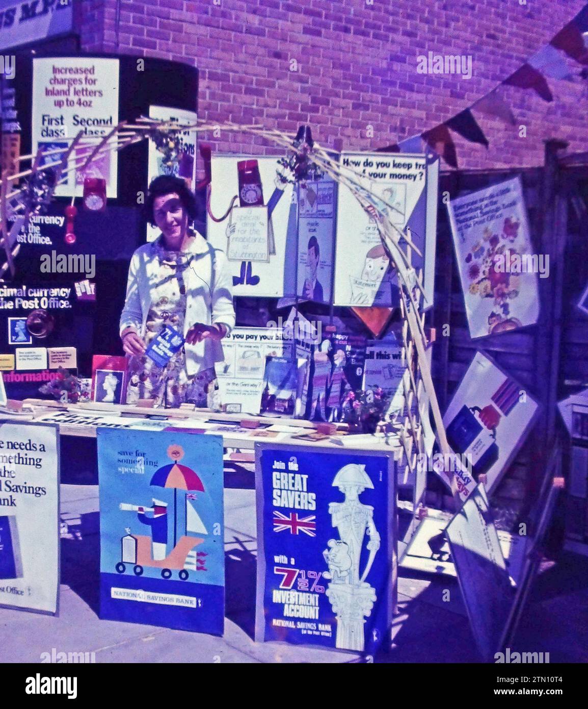 National Savings Bank UK. A woman standing at a stall promoting savings with an interest rate of  7 ½%, and other products with the National Savings Bank in 1970, when interest rates were high. Stock Photo